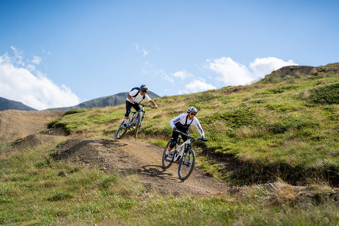 Two Cyclists Speed Along on Their MTBs Through the Bends of the H-Dream
